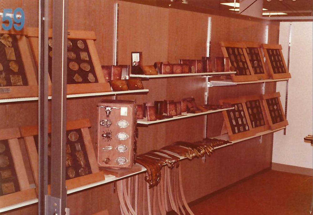 Display case with various belts and belt buckles on shelves in a store setting
