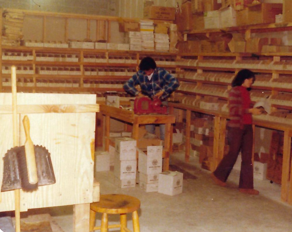 Two people working in a storage room with shelves and boxes.